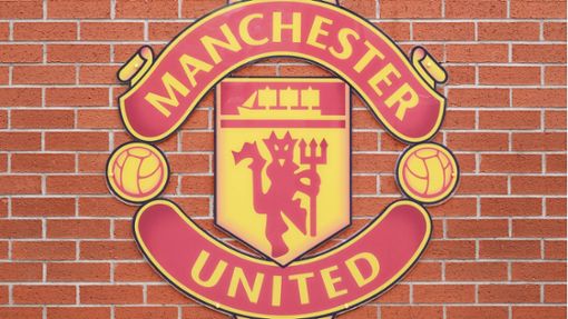 Das Logo von Manchester United an der Wand des Fußballstadions Old Trafford. Ein britischer Unternehmer übernimmt bis zu 25 Prozent der Anteile des Vereins. Foto: imago/imagebroker/imageBROKER/Simon Belcher