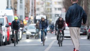 Ein junger Mann fährt auf einem E-Scooter eine Straße in Stuttgart entlang, während ihm drei Fahrradfahrer entgegenkommen Foto: dpa/Gregor Bauernfeind
