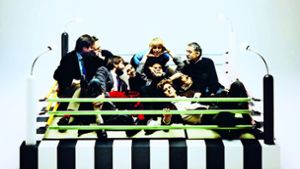 Übermütig: das „Memphis“-Team 1981 auf dem Bett „Masanori“ von Umeda Tawaraya – ganz rechts mit Schnauzer Ettore Sottsass Foto: Studio Azzurro, courtesy Memphis, Milano