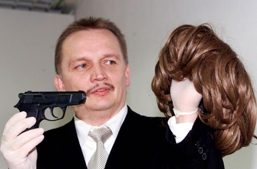 Der Ermittler zeigt eine Waffe und Frauenperücke der Serienbankräuber, die 2003 gefasst wurden. Foto: Kraufmann/Susanne Ker/n; Polizei (2)