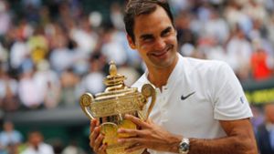 Roger Federer mit der Trophäe, die er am häufigsten in Händen hielt: Der Schweizer siege achtmal auf dem Heiligen Rasen von Wimbledon. Foto: AFP/ADRIAN DENNIS