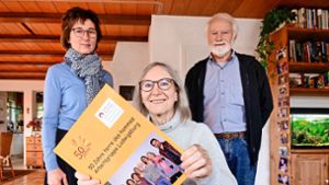 Brigitte Thinschmidt (von links),  Rose und Karl Herrigel schwelgen in Erinnerungen, wenn sie sich den Fotoband zum 50-jährigen Bestehen der Arbeitsgruppe anschauen. Foto: Simon Granville