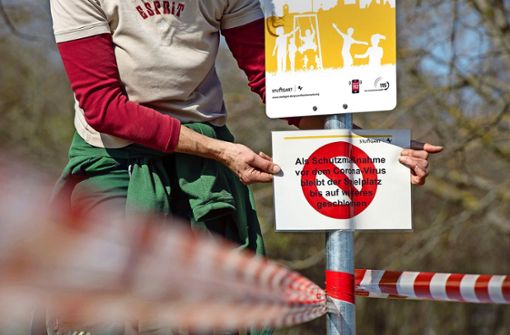 Eine Mitarbeiterin befestigt ein Warnschild auf dem Spielplatz am Killesberg.Foto: Lichtgut/Leif Piechowski Foto:  