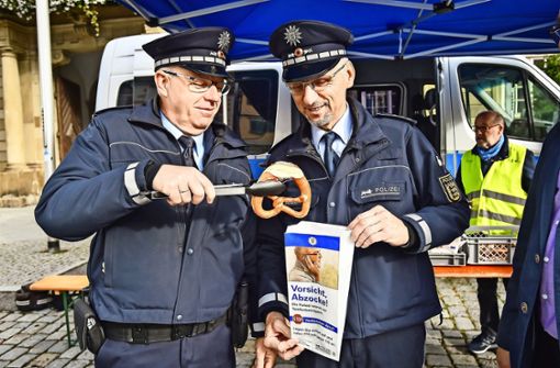 Die Polizisten Alfred Seiter (links) und Paul  Mejzlik zeigen bei einer Aktion gegen Telefonbetrüger in diesem Monat in  Esslingen eine Brötchentüte mit der Aufschrift  „Vorsicht Abzocke! Die Polizei warnt vor Telefonbetrügern“. Foto: dpa/Ferdinando Iannone