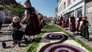 Im  baden-württembergischen  Hüfingen ziehen  Trachtenträgerinnen  an Fronleichnam 2017  während der Prozession an einem prächtig geschmückten Blumenteppich vorbei. Foto: Patrick Seeger/dpa