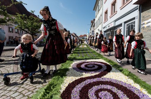Im  baden-württembergischen  Hüfingen ziehen  Trachtenträgerinnen  an Fronleichnam 2017  während der Prozession an einem prächtig geschmückten Blumenteppich vorbei. Foto: Patrick Seeger/dpa