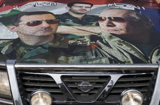 Eine Collage mit dem russischen Diktator Baschar al-Assad (links) und Russlands Präsident Wladimir Putin auf der Motorhaube eines Autos in Syrien. Foto: AP