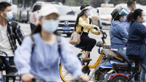 Menschen in Wuhan tragen Mund-Nasenbedeckungen, während sie zur morgendlichen Rush Hour im Stadtverkehr. (Archivbild) Foto: dpa/kyodo