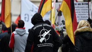 Ein Demonstrant steht Anfang 2017 in Köln zwischen Deutschlandfahnen und hat einen Pullover mit der Aufschrift „Defense Germany“ an. Foto: dpa