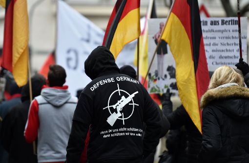 Ein Demonstrant steht Anfang 2017 in Köln zwischen Deutschlandfahnen und hat einen Pullover mit der Aufschrift „Defense Germany“ an. Foto: dpa