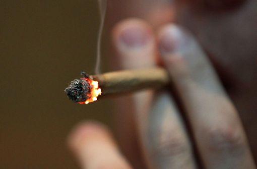 Der Angeklagte zündet sich eine Marihuana-Zigarette an. Foto: picture alliance/dpa
