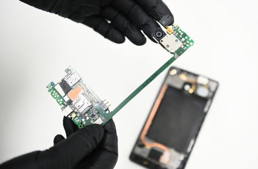 Ein IT-Forensiker zeigt die Hauptplatine eines Smartphones. Foto: dpa/Nicolas Armer