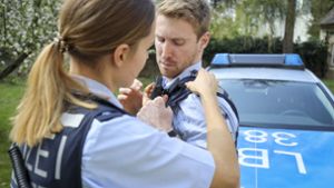 Die Streifenpolizistin Laura Geißler hilft ihrem Kollegen Nils Mayer, die kleine Kamera an der Schulter anzubringen. Foto: factum/Simon Granville
