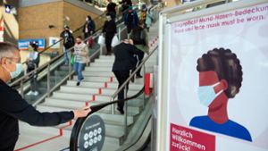 Brandenburg, Potsdam: Passanten mit Mundschutz gehen im Hauptbahnhof an einem Schild der Bahnhofs-Passagen mit der Aufschrift «Herzlich willkommen zurück! Tragepflicht Mund-Nasen-Bedeckung.» vorbei. Foto: picture alliance/dpa