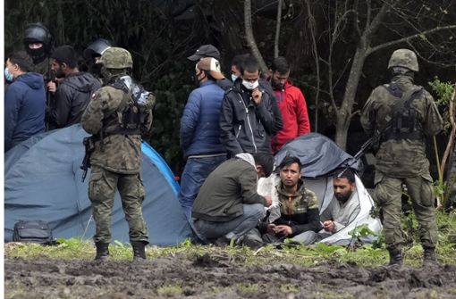 Polnische Sicherheitskräfte umringen Migranten, die an der Grenze zu Belarus festsitzen. Polen hat wegen der vielen Flüchtlinge den Ausnahmezustand an der EU-Außengrenze verhängt. Foto: dpa/Czarek Sokolowski