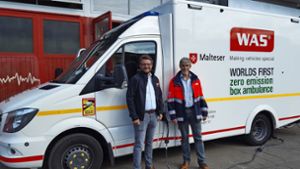 Joachim Fässler (r.), Geschäftsführer Malteser-Rettungsdienst Bezirk Stuttgart, und Christoph Stegemann (WAS GmbH) zeigen den weltweit ersten Rettungswagen mit Elektro-Antrieb im Malteser Rettungsdienst Stuttgart. Foto: Mal/.