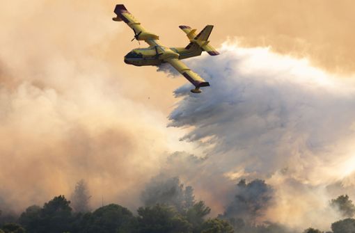 Ein Löschflugzeug lädt seine Fracht über einen Brandherd auf der Ferieninsel Čiovo ab. Foto: Miroslav Lelas/AP/Miroslav Lelas
