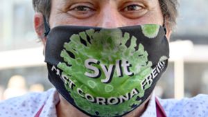 „Sylt Fast Corona Frei!!!“ steht auf der Maske, die ein Kellner in der Friedrichstraße in Westerland trägt. Foto: dpa/Carsten Rehder