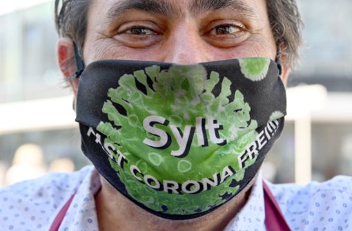 „Sylt Fast Corona Frei!!!“ steht auf der Maske, die ein Kellner in der Friedrichstraße in Westerland trägt. Foto: dpa/Carsten Rehder