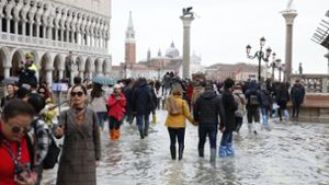 Touristen laufen auf dem überfluteten Markusplatz durch das Wasser. Der Bürgermeister von Venedig spricht von einer Katastrophe“, fast das komplette historische Zentrum steht unter Wasser. Foto: dpa/Andrea Gilardi