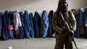 Ein Taliban-Kämpfer steht in Kabul Wache, während Frauen darauf warten, von einer Hilfsorganisation Lebensmittel zu erhalten. Foto: dpa/Ebrahim Noroozi