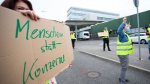Eine Demonstrantin hat vor dem Stuttgarter Flughafen ein Schild mit der Aufschrift „Menschen statt Konzerne“ in der Hand. Foto: dpa/Tom Weller