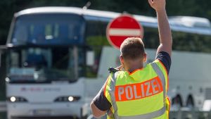 Ein Bundespolizist hält an einer Kontrollstelle an der Autobahn A 3 kurz hinter der deutsch-österreichischen Grenze nahe Pocking (Bayern) einen Bus an. Foto: dpa