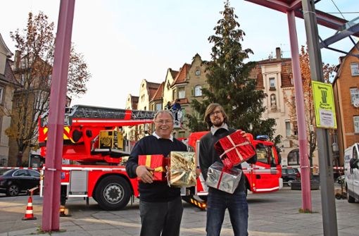 Peter Schmaus und Sohn Dominik halten  hier noch   einige der   Päckchen in Händen, die  inzwischen den Weihnachtsbaum auf dem Wilhelm-Geiger-Platz  schmücken. Foto: Georg Friedel