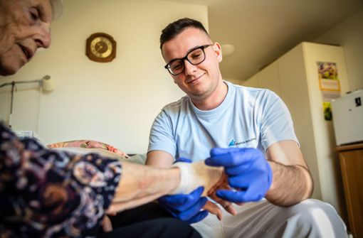 Ruzhdi Canaj ist beruflich aufgestiegen. Hier verbindet er das Handgelenk einer Bewohnerin des Pflegeheims. Foto: Lichtgut/Julian Rettig