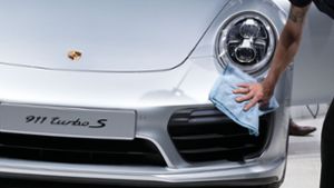Ein Mitarbeiter säubert am während der Hauptversammlung 2016 der Volkswagen AG in Hannover (Niedersachsen) einen Porsche 911 Turbo S. Foto: dpa