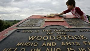Ein Mädchen beugt sich über eine Gedenktafel für das das legendäre Rock-Festival Woodstock in Bethel (New York). Das geplante Jubiläums-Festival Woodstock 50 nordwestlich von New York soll trotz Absage eines Investors stattfinden. Foto:  
