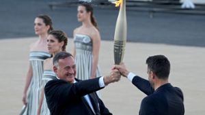 Der Präsident des französischen Organisationskomitees, Tony Estanguet (r), nahm die olympische Flamme in Athen entgegen. Foto: Petros Giannakouris/AP/dpa