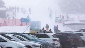 Menschen stehen im dichten Nebel nahe dem Skilift am Haldenköpfle, während im Vordergrund der volle Parkplatz der geschlossenen Liftanlage zu sehen ist. Foto: dpa/Philipp von Ditfurth