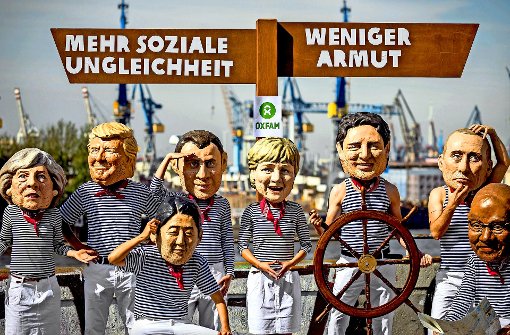Aktivisten haben sich mit Masken von G-20-Regierungschefs an den Landungsbrücken Hamburg platziert. Foto: dpa