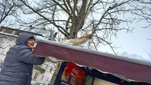 Mit dem Besen wird das Dach des Kiosks von Schnee befreit. Foto: /Eva Schäfer