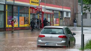 Passanten stapfen und fahren durch das Hochwasser  in Saarbrücken. Foto: dpa/Harald Tittel