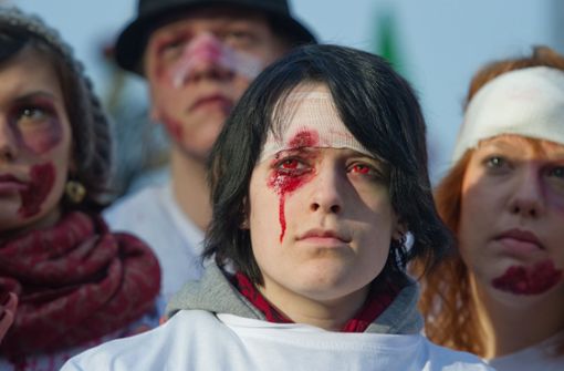 Jugendliche, die symbolisch Verletzungen an Augen und Kopf zeigen, demonstrieren gegen den gewaltsamen Polizeieinsatz am 30. September 2010. Foto: dpa