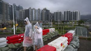 Menschen in Regenmänteln gehen in Hongkong  an Sandsackbarrikaden vorbei Foto: dpa/Billy H.C. Kwok