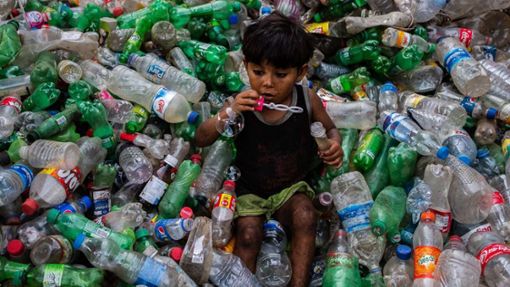 Ein Junge pustet Seifenblasen, während er auf einem Stapel von Plastikflaschen in einer Recycling-Anlage in Dhaka (Bangladesch) sitzt. Foto: Nayem Shaan/ZUMA Wire/dpa