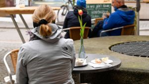 Eine Frau sitzt in Tübingen beim Kaffeetrinken. Foto: AFP/THOMAS KIENZLE