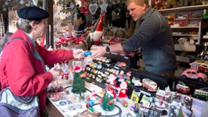 Kevin Maurer (rechts) hat seinen ersten Tag auf dem Weihnachtsmarkt. Die kleinen Blechautos locken jedes Jahr viele Stammkunden (links) an den Stand seiner Chefin. Foto: Oliver Willikonsky / Lichtgut