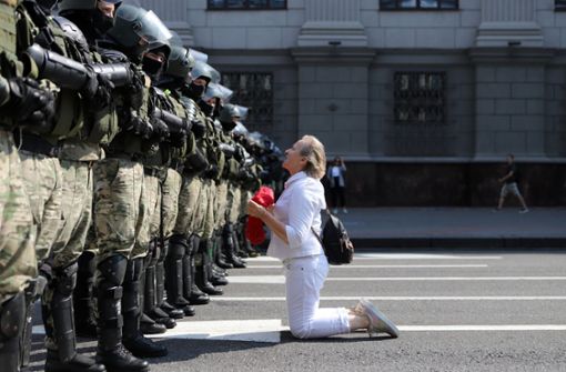 Minsk: Eine Demonstrantin kniet vor Bereitschaftspolizisten während eines Protestes am Unabhängigkeitsprospekt Foto: dpa