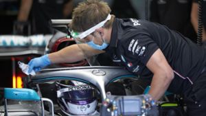 Safety first: Ein Mercedes-Mechaniker reinigt das Visier von Lewis Hamiltons Helm bei des Testfahrten in Silverstone – er trägt ein Gesichtsvisier sowie einen Mund-Nasen-Schutz. Foto: Daimler AG/Steve Etherington