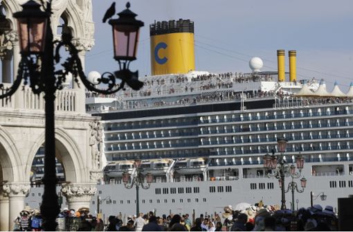 Das Kreuzfahrtschiff „Costa Deliziosa“ fährt am Markusplatz vorbei, auf dem zahlreiche Touristen unterwegs sind. Foto: dpa