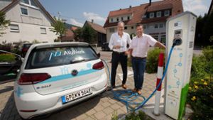 Der Lenninger Bürgermeister Michael Schlecht (rechts) und der EVL-Geschäftsführer Christian Gropp hängen das geliehene E-Mobil ans Kabel. Foto: Ines Rudel