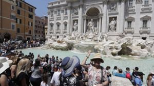 Immer über die Schulter: eine Touristin wirft Geld in den Trevi-Brunnen in Rom. Foto: AP