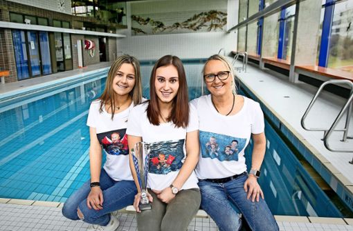 Die beiden Ex-Babyschwimmerinnen Anna Hogh und  Corinna Mödinger  mit der  Trainerin Nicole Hogh (von links) in T-Shirts mit alten Fotos vom Winter  1997/98 Foto: Horst Rudel