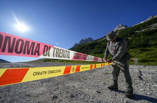 Ein Beamter der italienischen Finanzpolizei blockiert den Zugang zum Marmolada-Berg und zum Punta-Rocca-Gletscher in den italienischen Alpen mit Absperrband. Foto: dpa/Luca Bruno