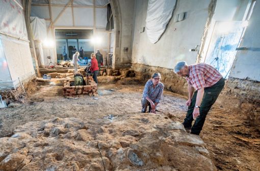 Der Kreisarchäologe Reinhard Rademacher begutachtet mit einer Kollegin einen Unterbau aus Stein, den sie in der Erde unter dem früheren Boden der Cäcilienkirche in Uhingen entdeckt haben. Foto: Giacinto Carlucci