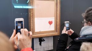 Besucher lichten das geschredderte Werk „Love is in the Bin“ in Baden-Baden mit ihren Smartphones ab. Foto: AFP